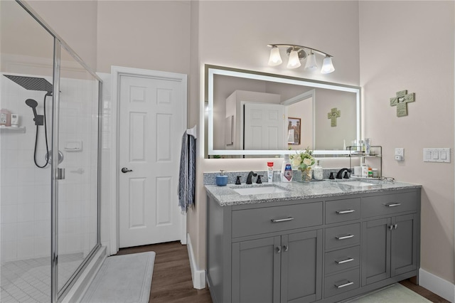 bathroom with hardwood / wood-style floors, vanity, and a shower with shower door