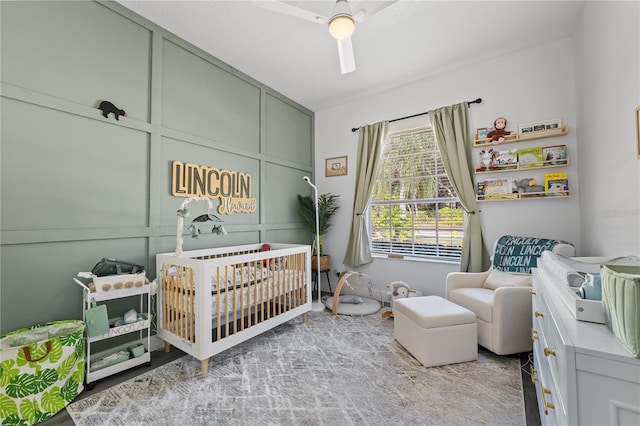 bedroom featuring a crib, light carpet, and ceiling fan