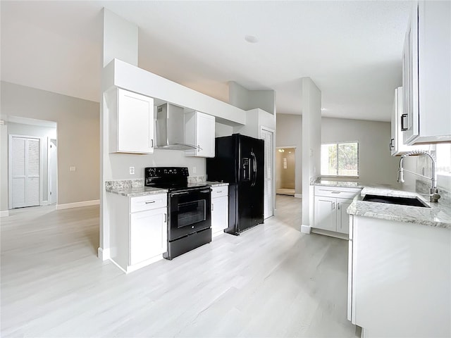 kitchen featuring white cabinets, wall chimney exhaust hood, black appliances, and light wood-type flooring