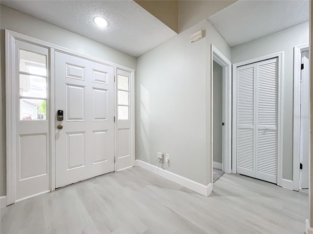 foyer with light wood-type flooring and a textured ceiling