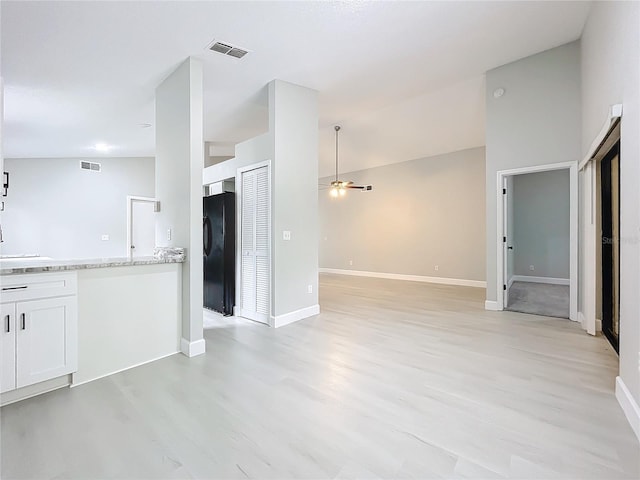 unfurnished living room featuring ceiling fan, light wood-type flooring, and high vaulted ceiling