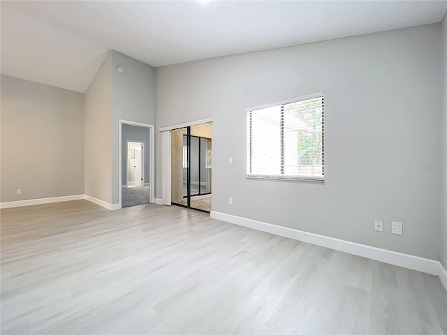 spare room featuring light wood-type flooring and high vaulted ceiling