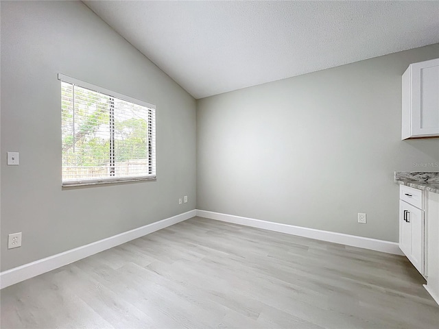 interior space featuring a textured ceiling, light hardwood / wood-style floors, and vaulted ceiling