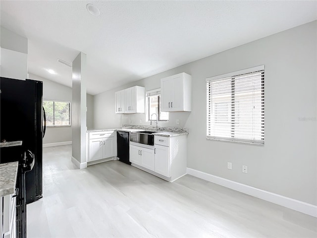 kitchen featuring light stone counters, vaulted ceiling, sink, black appliances, and white cabinets