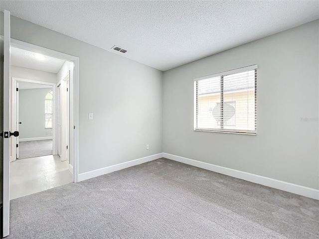 carpeted empty room featuring a textured ceiling