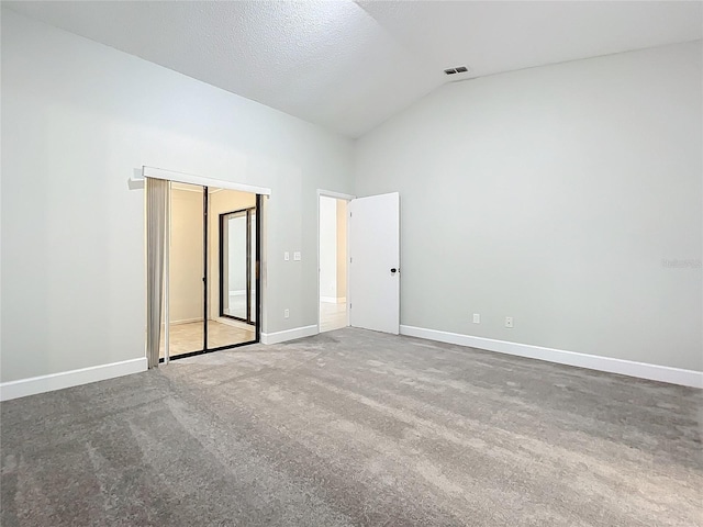 empty room featuring carpet flooring, a textured ceiling, and high vaulted ceiling