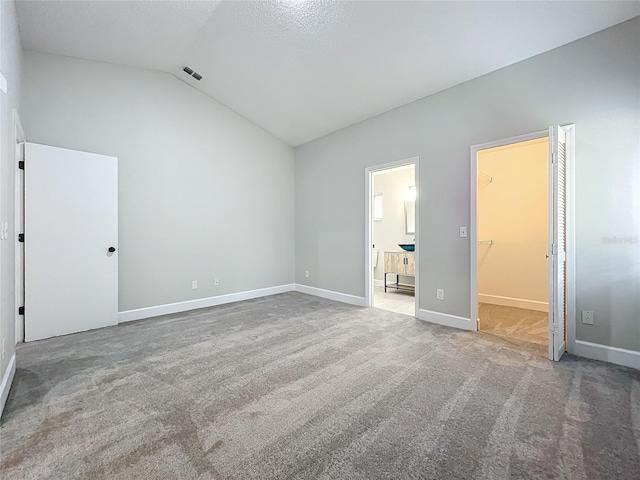 unfurnished bedroom featuring carpet flooring, connected bathroom, a spacious closet, lofted ceiling, and a closet