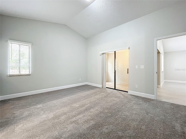 unfurnished room with carpet, a textured ceiling, and lofted ceiling