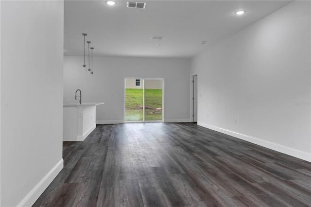 unfurnished living room featuring sink and dark hardwood / wood-style flooring