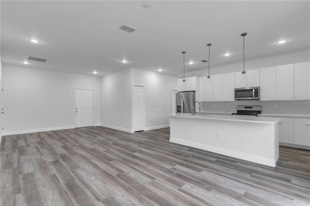 kitchen featuring white cabinetry, decorative light fixtures, a center island with sink, and appliances with stainless steel finishes