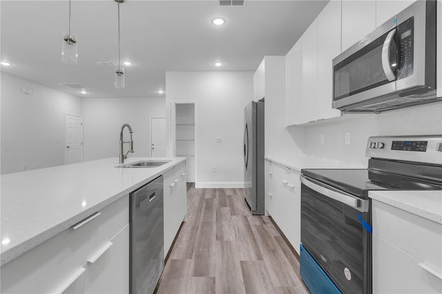 kitchen with pendant lighting, sink, white cabinets, light stone counters, and stainless steel appliances