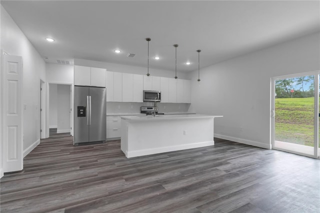 kitchen with pendant lighting, appliances with stainless steel finishes, a kitchen island with sink, and white cabinets