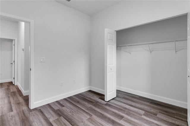 unfurnished bedroom with dark hardwood / wood-style floors and a closet