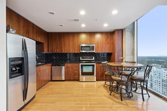 kitchen featuring decorative backsplash, light hardwood / wood-style floors, sink, and stainless steel appliances