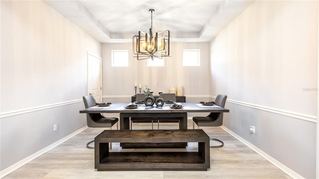 dining room with a notable chandelier, light hardwood / wood-style flooring, and a tray ceiling