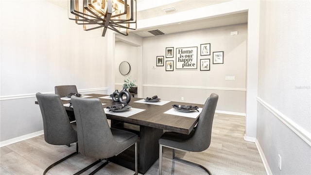 dining area with light hardwood / wood-style floors and an inviting chandelier