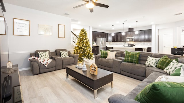 living room with ceiling fan, sink, and light hardwood / wood-style floors