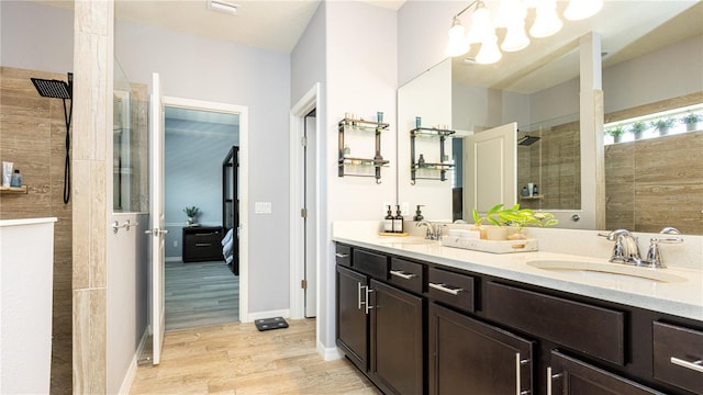 bathroom with tiled shower, vanity, hardwood / wood-style flooring, and a notable chandelier