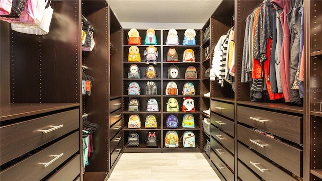 walk in closet with light hardwood / wood-style floors