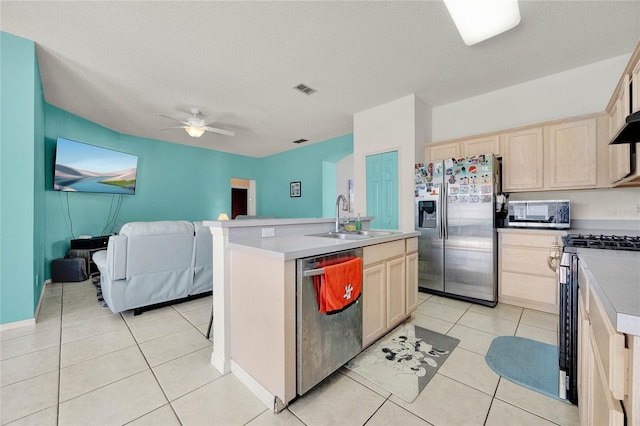 kitchen with ceiling fan, sink, stainless steel appliances, a textured ceiling, and a kitchen island with sink