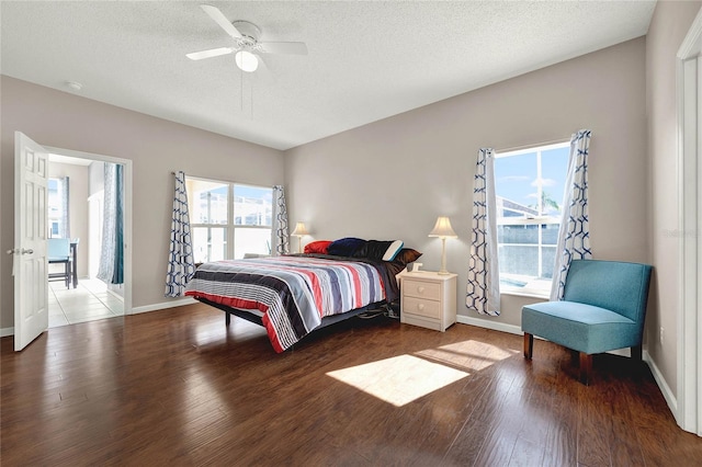 bedroom featuring ceiling fan, wood-type flooring, a textured ceiling, and multiple windows