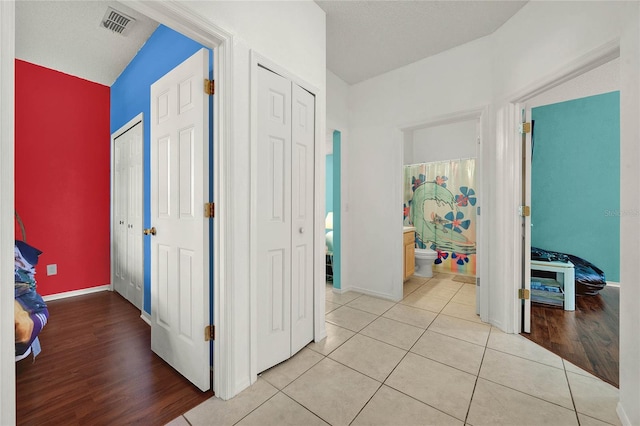 hallway with a textured ceiling, light wood-type flooring, and lofted ceiling