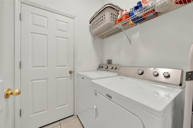 laundry area with washer and clothes dryer and light tile patterned floors