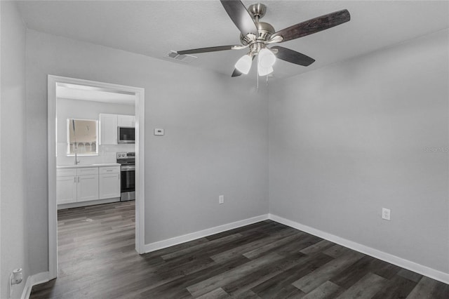 empty room with ceiling fan and dark hardwood / wood-style flooring