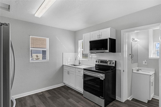 kitchen with backsplash, stainless steel appliances, dark wood-type flooring, sink, and white cabinets