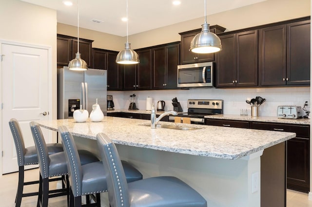 kitchen with pendant lighting, a center island with sink, a breakfast bar area, tasteful backsplash, and stainless steel appliances