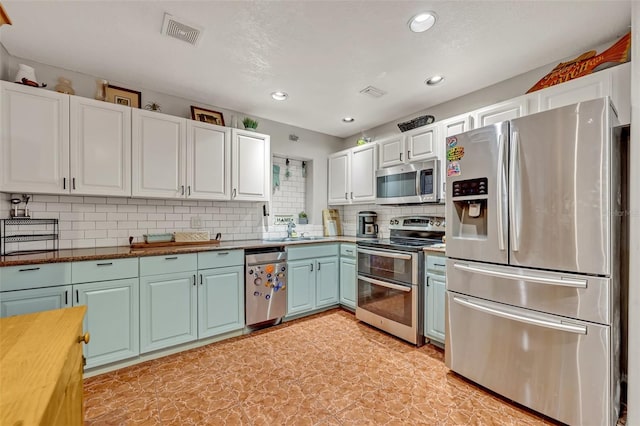 kitchen with tasteful backsplash, white cabinetry, sink, and appliances with stainless steel finishes