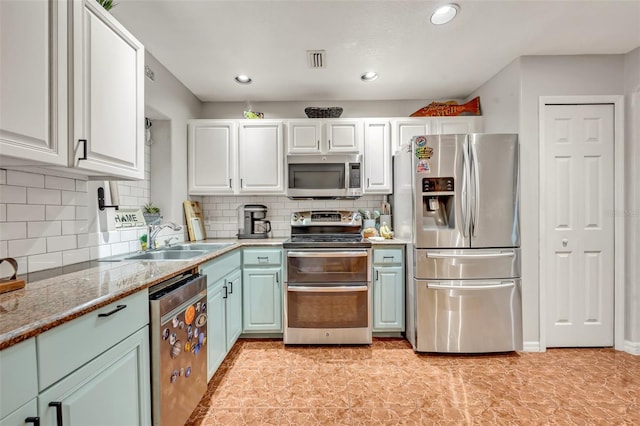 kitchen featuring light stone countertops, backsplash, stainless steel appliances, sink, and white cabinets