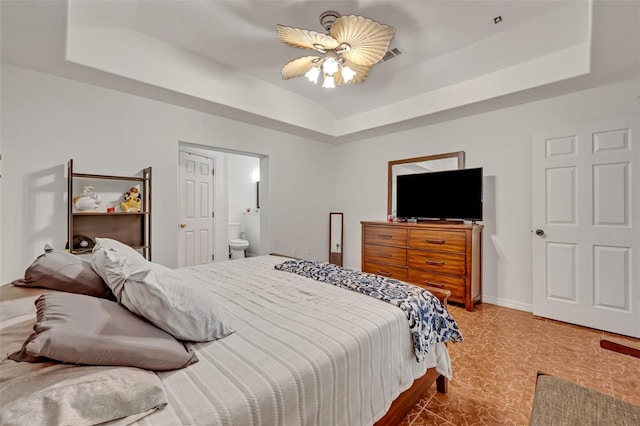 bedroom featuring ensuite bathroom, a raised ceiling, and ceiling fan