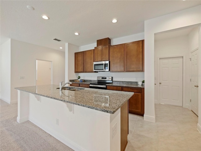 kitchen with a breakfast bar, appliances with stainless steel finishes, an island with sink, and sink