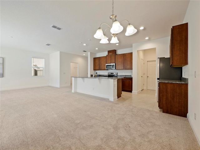 kitchen featuring a kitchen island with sink, appliances with stainless steel finishes, decorative light fixtures, a kitchen bar, and a chandelier