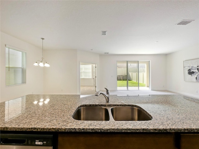 kitchen with light stone counters, stainless steel dishwasher, sink, pendant lighting, and an inviting chandelier