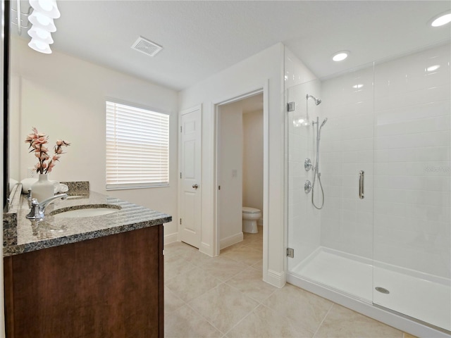 bathroom featuring tile patterned flooring, vanity, an enclosed shower, and toilet