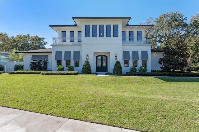 view of front facade with a front yard, french doors, and a balcony