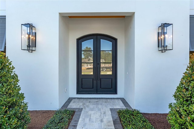 view of exterior entry featuring french doors and stucco siding