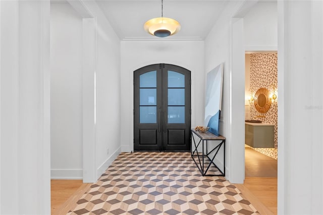 foyer entrance with arched walkways, french doors, and baseboards