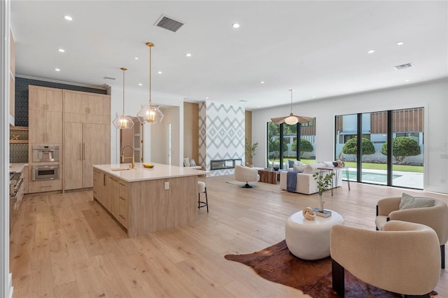 kitchen with open floor plan, hanging light fixtures, an island with sink, and light countertops