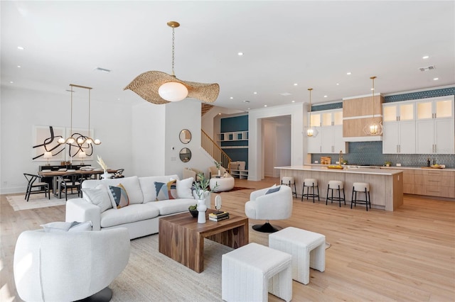 living room featuring stairway, light wood-style flooring, visible vents, and recessed lighting