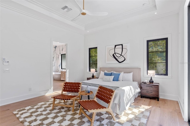 bedroom with ornamental molding, a tray ceiling, visible vents, and light wood-style floors