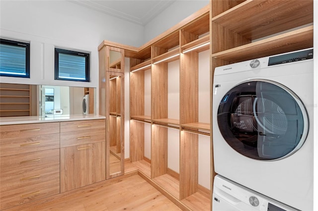 laundry room with stacked washer / dryer, laundry area, and light wood-style flooring