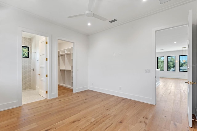 unfurnished bedroom with light wood-style flooring, baseboards, a walk in closet, and connected bathroom