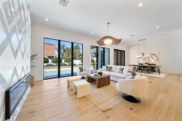 living room with light wood-type flooring, visible vents, baseboards, and recessed lighting