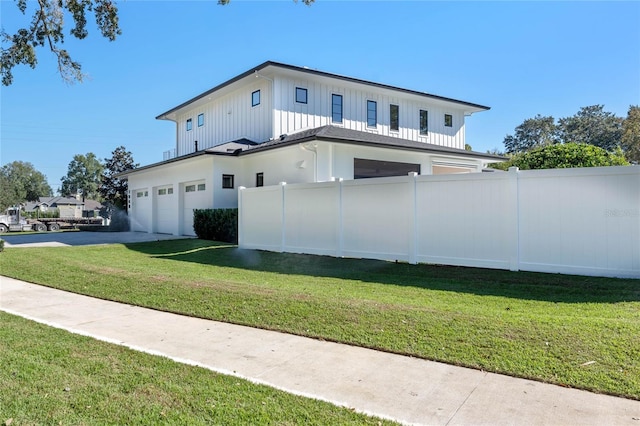 view of home's exterior with a yard, an attached garage, board and batten siding, fence, and driveway