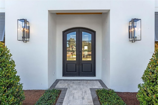 property entrance with stucco siding and french doors