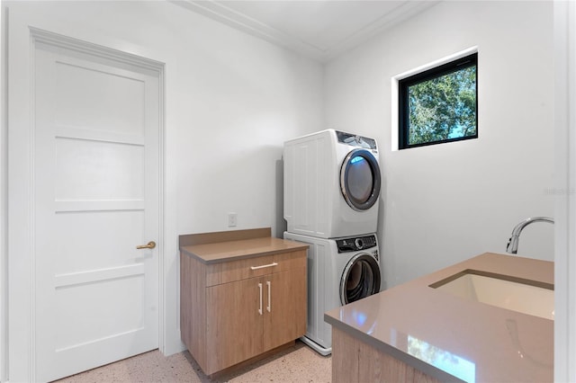 washroom with a sink, cabinet space, and stacked washer / drying machine