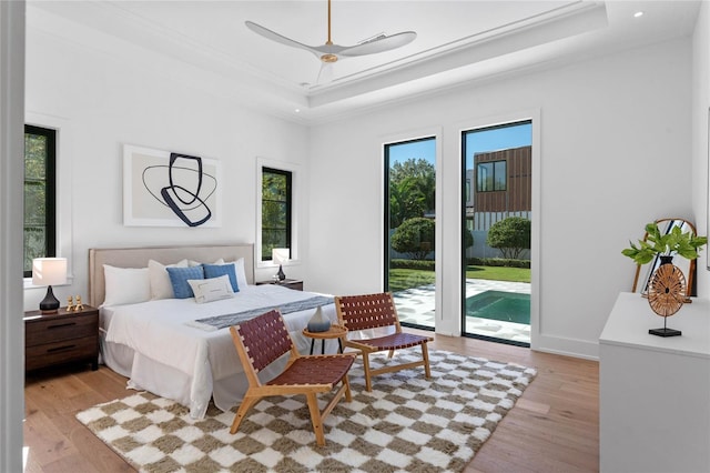 bedroom featuring light wood-style floors, access to outside, ornamental molding, and a raised ceiling